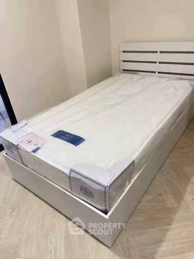 Modern bedroom with sleek white bed frame and new mattress in minimalist design.