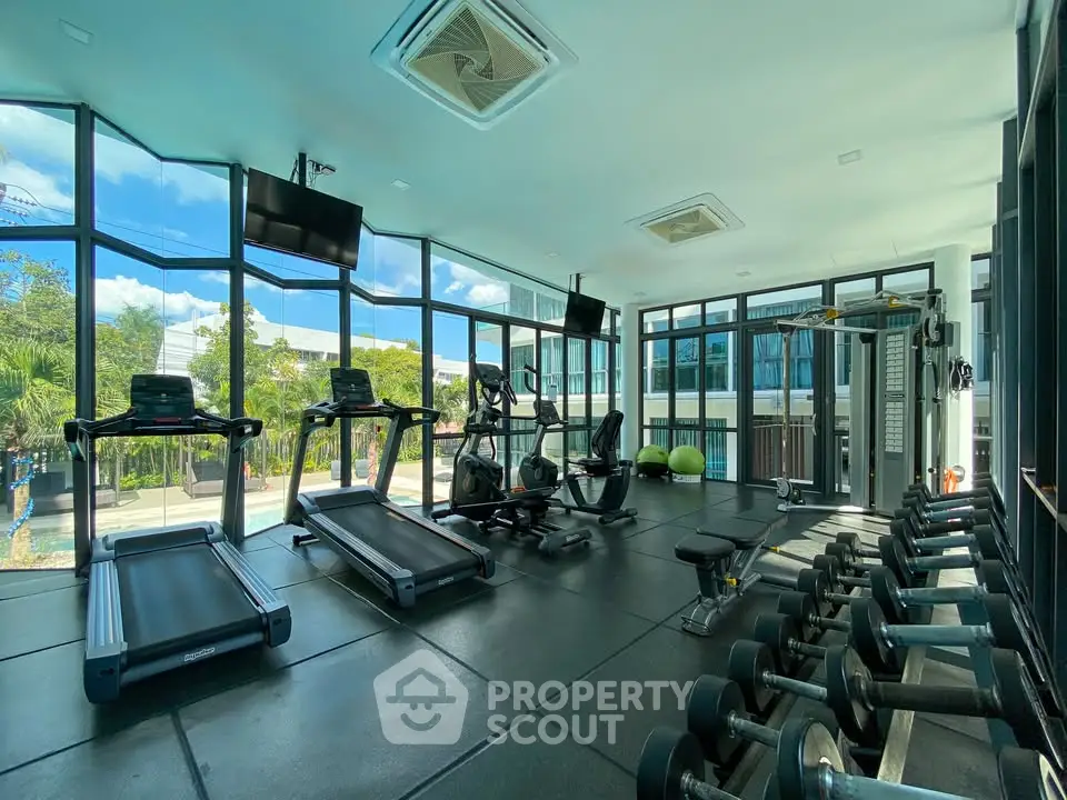 Modern gym with large windows and fitness equipment in a residential building.