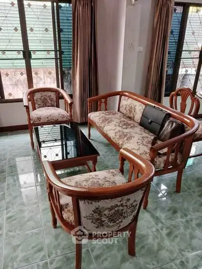 Charming living room with vintage wooden furniture and large windows for natural light.