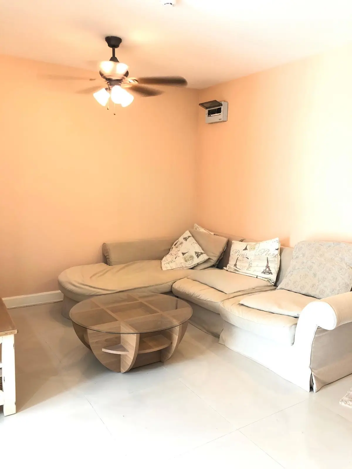 Cozy living room with beige sectional sofa and modern glass coffee table, perfect for relaxation.