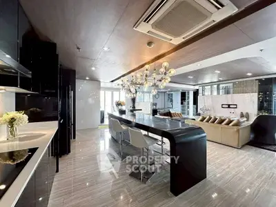 Luxurious open-layout kitchen and living room with modern chandelier and sleek design.