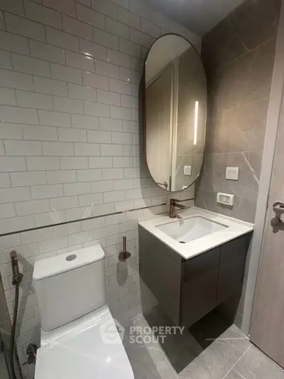 Modern bathroom with sleek design, featuring a stylish oval mirror and contemporary fixtures.