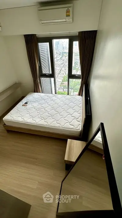 Modern bedroom with city view, featuring a comfortable bed and large windows for natural light.