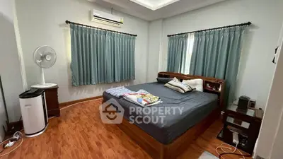 Spacious bedroom with wooden flooring and modern furnishings, featuring air conditioning and ample natural light.