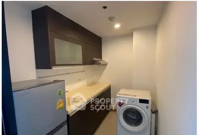 Modern kitchen with sleek cabinetry and washing machine in compact layout.