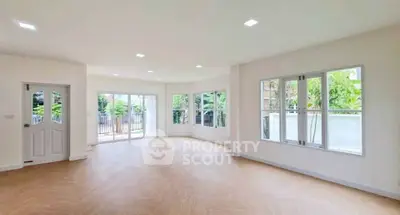 Spacious and bright living room with large windows and garden view, perfect for family gatherings.