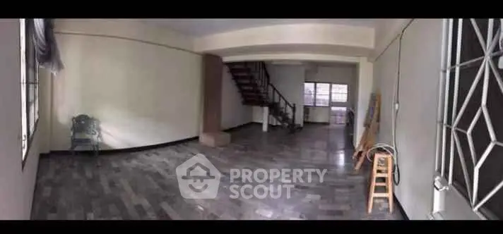 Spacious open-plan living area with staircase and large windows.