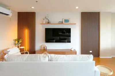 Modern living room with stylish decor and wall-mounted TV, perfect for relaxation.