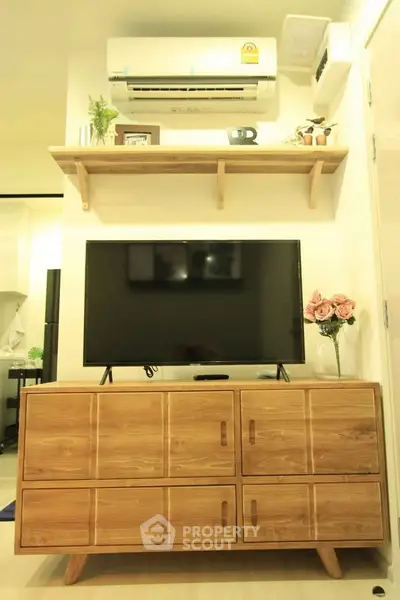 Modern living room with stylish wooden furniture and wall-mounted TV under air conditioning unit.