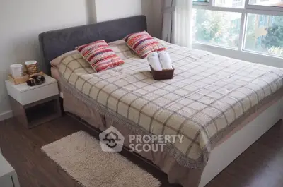Cozy bedroom with large window and stylish decor, perfect for relaxation.