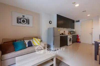 Modern living room with open kitchen, featuring a washing machine and stylish decor.