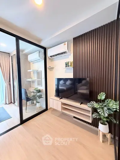 Modern living room with sleek design, featuring a TV, air conditioning, and stylish decor in a cozy apartment.