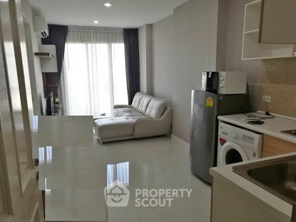 Modern apartment interior with sleek kitchen and cozy living area featuring a stylish sofa and natural light.
