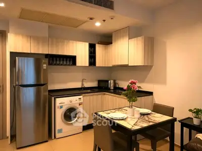 Modern kitchen with sleek cabinets, stainless steel fridge, and dining area in a cozy apartment.