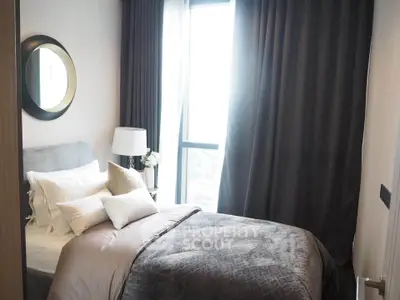 Cozy bedroom with elegant decor and large window offering natural light.