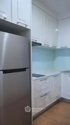 Modern kitchen with sleek white cabinets and stainless steel fridge