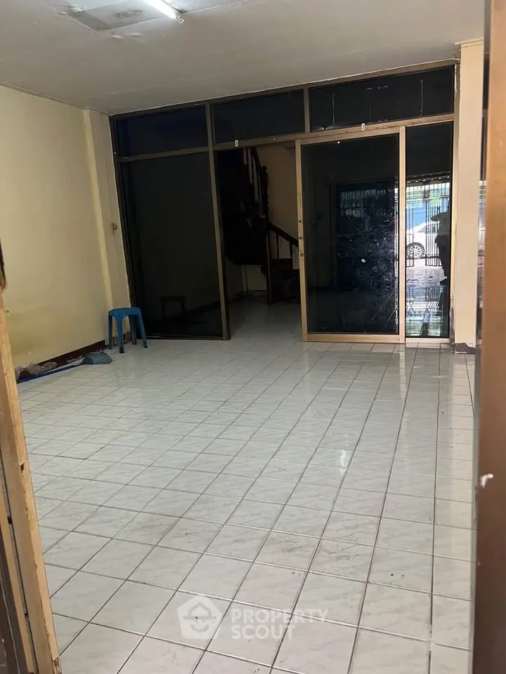 Spacious tiled room with glass doors and minimal furnishings, ideal for customization.