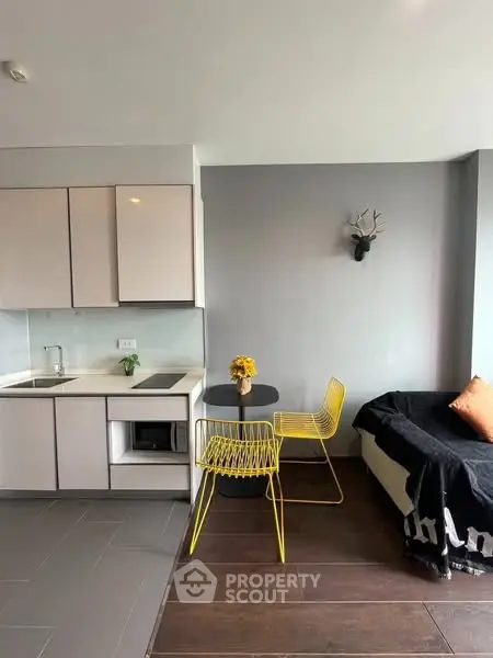 Modern studio apartment with sleek kitchen and stylish seating area.