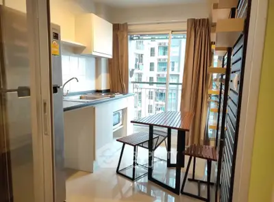 Modern kitchen with open layout and balcony view in urban apartment.