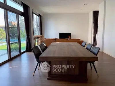Spacious modern living room with large windows and elegant dining area overlooking a serene outdoor view.
