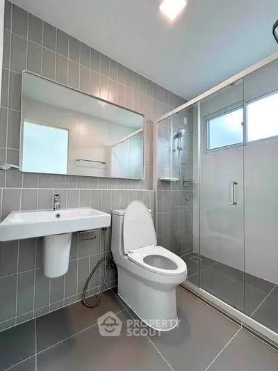 Modern bathroom with sleek design, featuring a glass shower and contemporary fixtures.