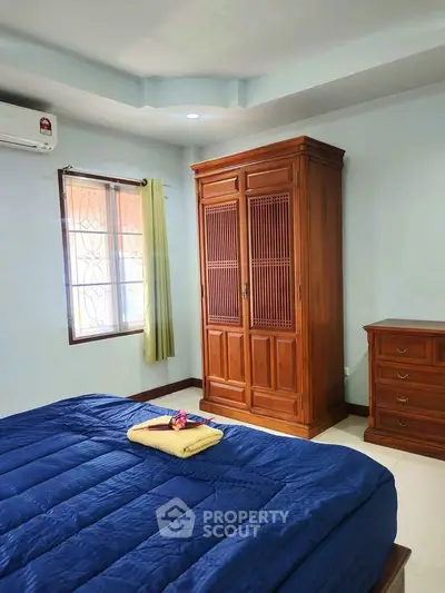 Cozy bedroom with wooden wardrobe and blue bedding, perfect for relaxation.