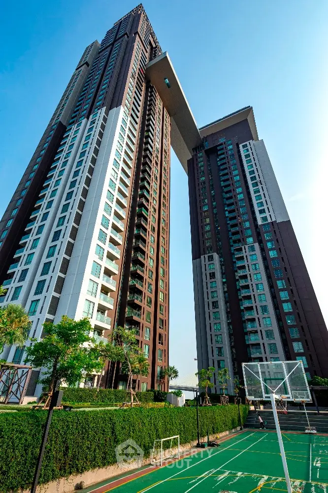 Stunning high-rise residential building with sports court and lush greenery