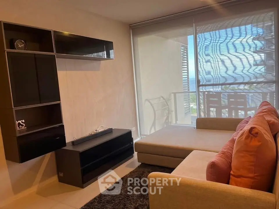 Modern living room with stylish furniture and large window offering natural light and balcony view.