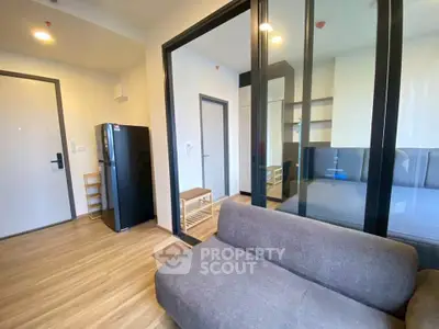 Modern apartment interior with glass partition, cozy sofa, and sleek flooring.