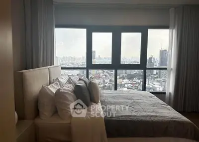Luxurious bedroom with stunning city view from high-rise apartment window.