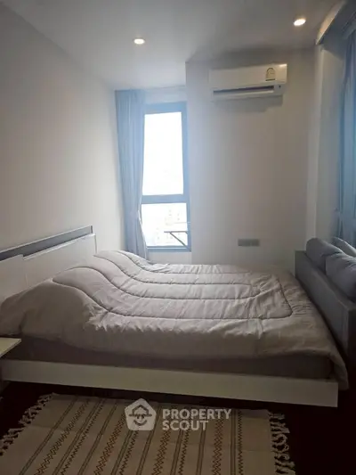 Cozy bedroom with modern decor and natural light from large window.