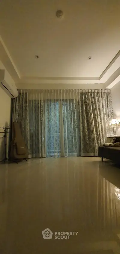 Spacious living room with elegant curtains and cozy lighting, perfect for relaxation.
