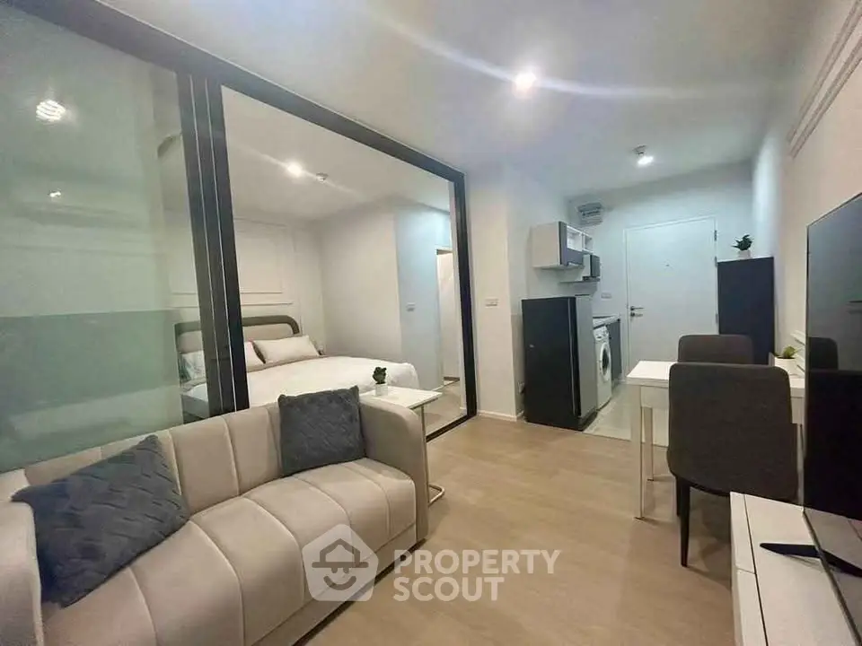 Modern open-plan living room with sleek kitchen and cozy bedroom in a stylish apartment.