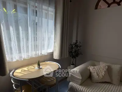Cozy living room with natural light, featuring a small table and comfortable sofa, perfect for relaxation.