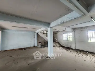 Spacious industrial-style interior with concrete floors and exposed beams, ideal for creative workspace or storage.