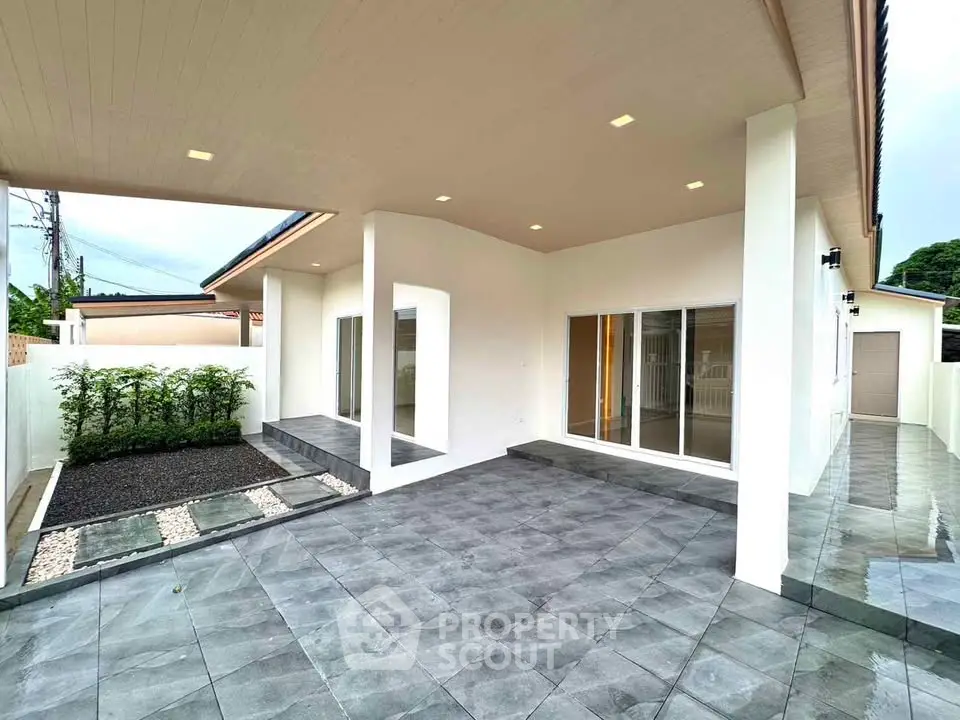 Modern home exterior with spacious tiled patio and garden area