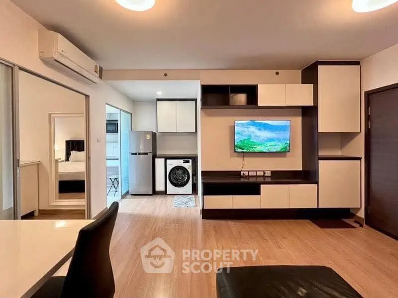 Modern living room with sleek furniture and integrated appliances in a stylish apartment.