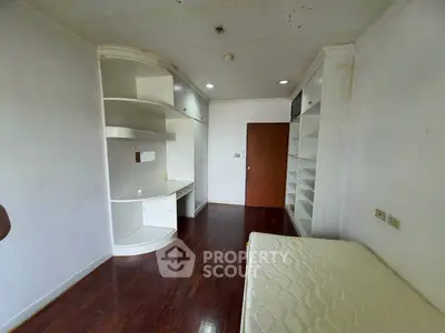 Spacious bedroom with built-in shelves and hardwood flooring