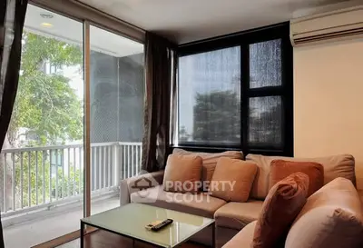 Cozy living room with large windows and balcony access, featuring modern furniture and air conditioning.
