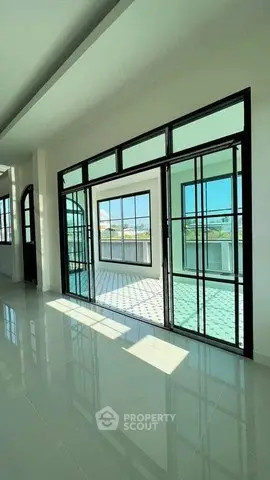 Spacious sunlit room with large windows and modern design, offering a bright and airy atmosphere.