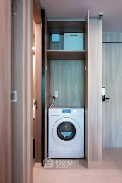 Modern apartment interior with built-in washing machine and sleek wooden cabinetry.