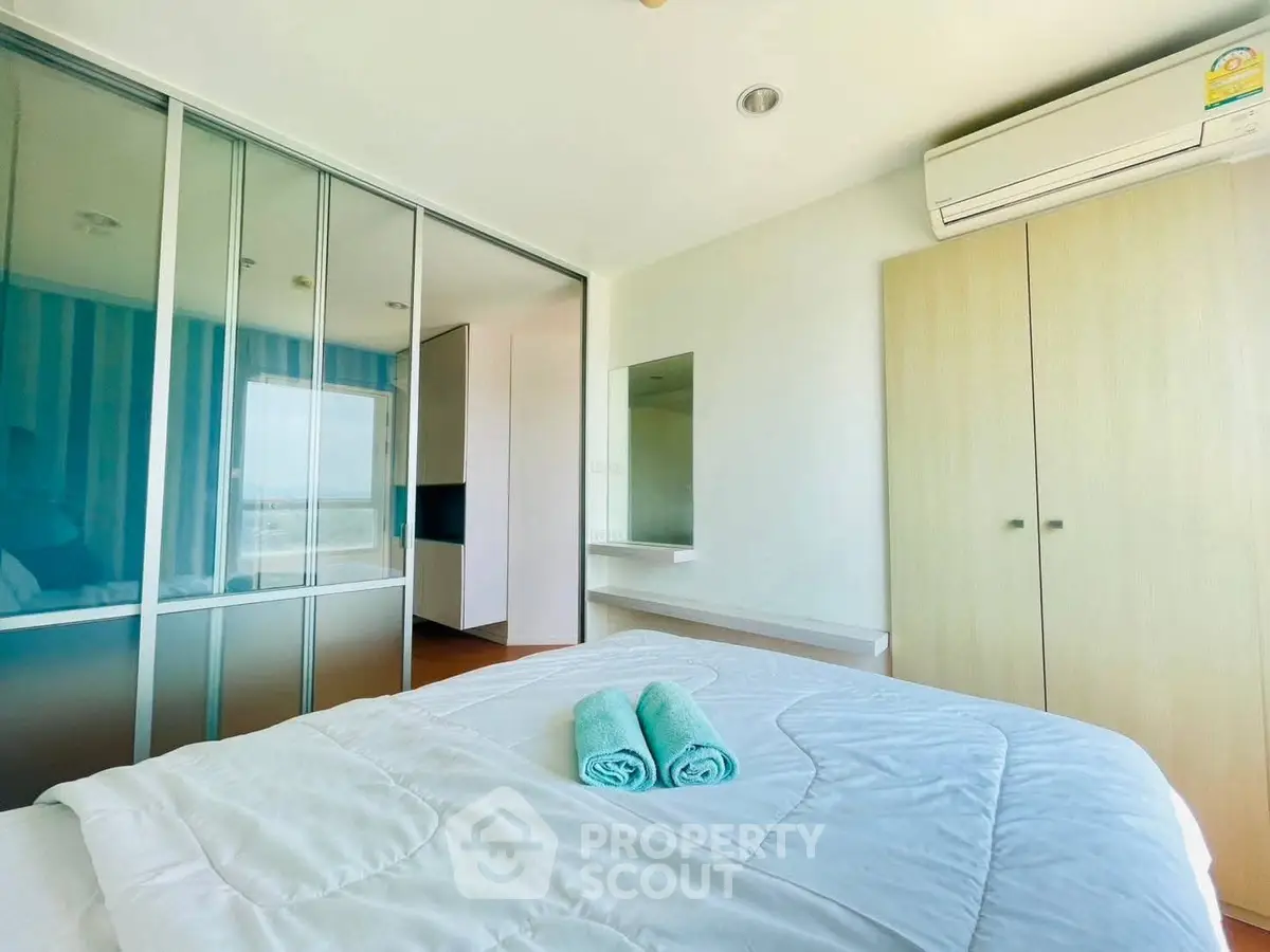 Bright bedroom with modern decor and air conditioning, featuring a large wardrobe and stylish bedding.