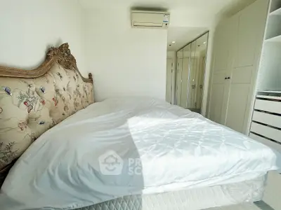 Luxurious bedroom with ornate headboard and mirrored wardrobe in bright natural light.