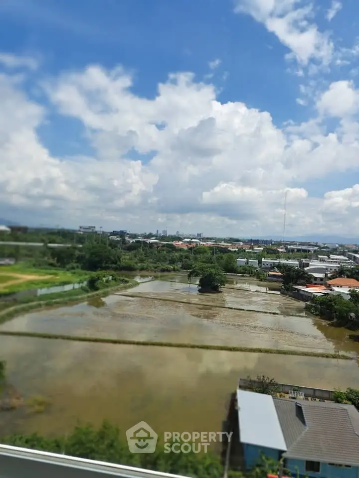 Stunning panoramic view of lush green fields and serene water bodies under a bright blue sky.