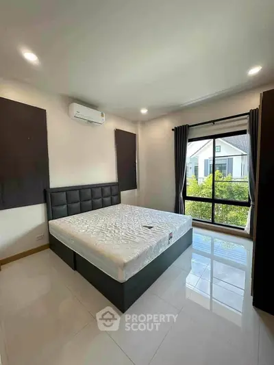 Modern bedroom with large window and garden view, featuring sleek design and natural light.