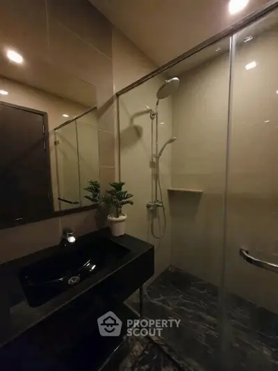 Modern bathroom with sleek black sink and glass shower enclosure