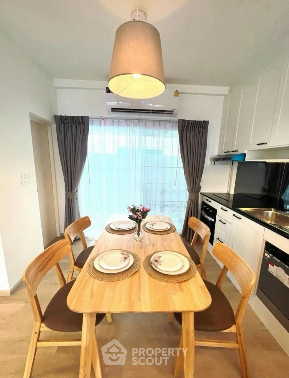 Modern kitchen with dining table set, sleek cabinetry, and natural light for a cozy dining experience.