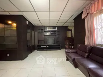 Spacious living room with dark wood paneling and leather sofa