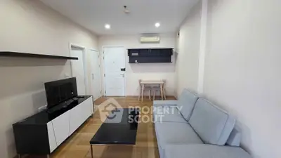 Modern living room with sleek furniture and neutral tones, featuring a cozy sofa and stylish entertainment unit.