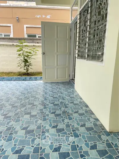 Charming patio with blue mosaic tiles and open door leading to a cozy interior space.